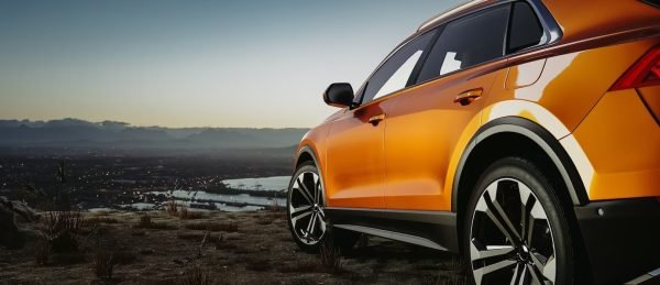 un SUV orange dans un paysage marécageus et un grand ciel bleu clair